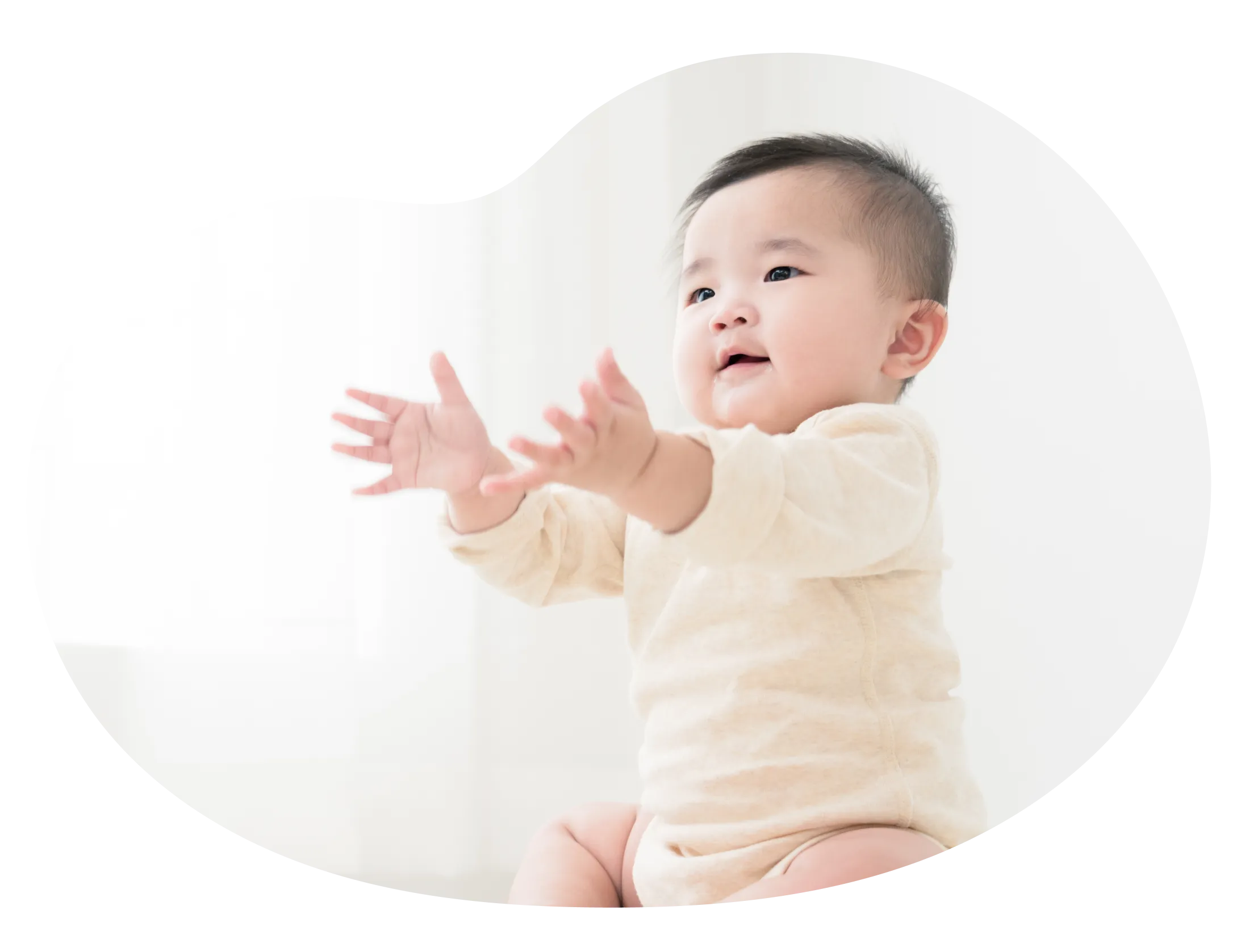 両手を前に出して見つめる赤ちゃんの写真
